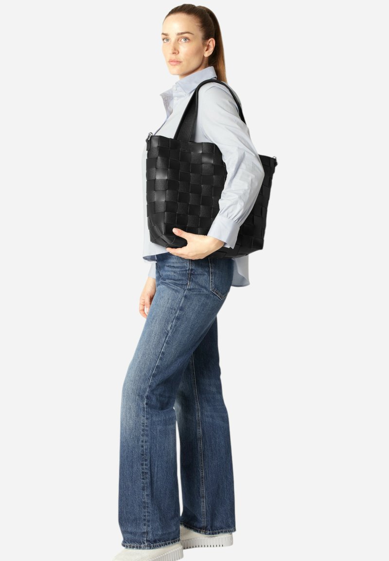 Bolso de tote tejido negro hecho de cuero, con asas anchas y una forma estructurada, mostrado sobre un fondo blanco liso.