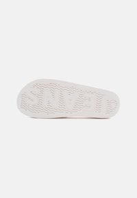Valge kummist treeningjalanike tald, millel on tekstuuriga põhi, zigzag-muster ja reljeefne "JEANS" logo. Sile viimistlus ja ümarad servad.