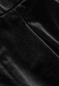 Crni baršunasti materijal sa mekanom, glatkom teksturom; ima suptilan sjaj i ujednačenu boju, naglašavajući njegov luksuzni izgled.