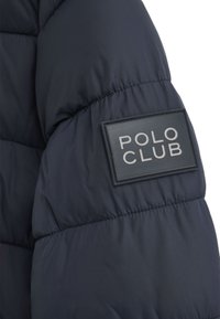 Granatowa puchowa kurtka z pikowanym wzorem i gumową naszywką "POLO CLUB" na rękawie. Materiał wydaje się gładki i lekki.