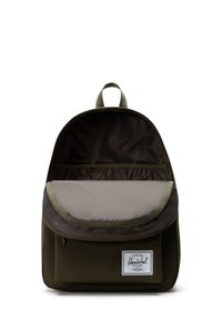 Green fabric backpack with a rounded shape, front pocket, and a mesh compartment inside, featuring a brand label on the front.