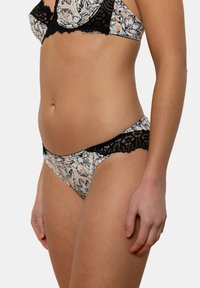 Bikini en beige et noir avec des bordures en dentelle florale, présentant un tissu à motifs avec une texture douce et un design taille basse.