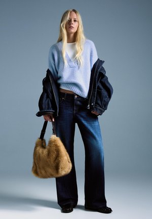 Svetlomodrý pletený sveter, biela košeľa pod ním, tmavé džínsy rozšírené na spodku, veľká tmavomodrá džínová bunda a hnedá kožušinová kabelka.