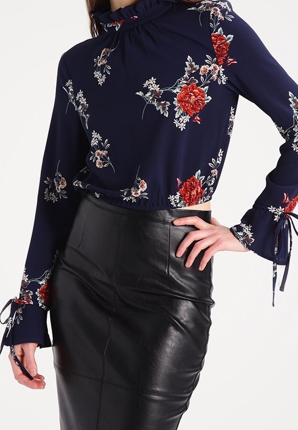 Námořnická halenka s dlouhým rukávem a květinovým vzorem, s volány na manžetách, spárovaná s černou koženou sukní s vysokým pasem.