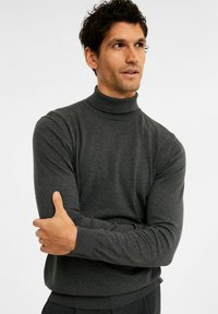 Dunkelgrauer Rollkragenpullover aus weichem Strickstoff, mit langen Ärmeln und gerippten Bündchen, in taillierter Form.