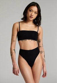 Črno dvodelno kopalke z bandeau zgornjim delom s tankimi naramnicami in spodnjim delom z visokim pasom. Gladek tekstura in minimalističen dizajn.
