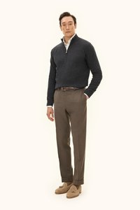 Ein grauer Reißverschluss-Pullover, braune maßgeschneiderte Hose und beigefarbene Loafers mit Quasten. Das Outfit zeichnet sich durch ein strukturiertes, modernes Design aus.