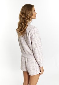 Compleu coordonat din tweed de culoare mov deschis, format dintr-o jachetă texturată și pantaloni scurți, cu un material moale și o talie și manșete cu nervuri.