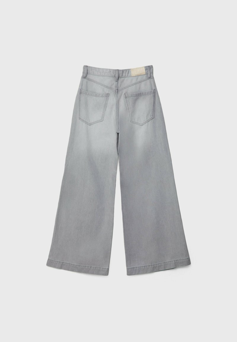 Pantalons en denim gris clair à jambes larges, taille haute, avec deux poches arrière et une finition propre. Texture douce et ourlet droit.