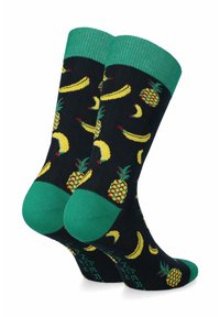 Granatowe skarpetki z zielonym mankietem i piętą, ozdobione wzorem żółtych bananów i ananasów. Wykonane z miękkiego, elastycznego materiału dla wygody.