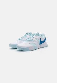 Pari urheilukenkiä, joissa on valkoista ja vaaleansinistä väriä, sekä sinisiä Nike-merkkejä, vaaleaa valkoista taustaa vasten.