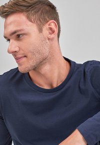 Mørkeblå langærmet t-shirt lavet af glat bomuld, med en klassisk rund halsudskæring og subtile syninger.