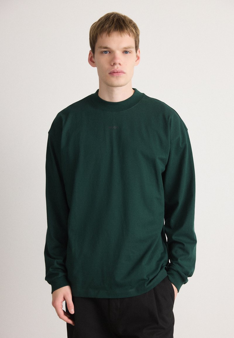 Zielony sweatshirt z długim rękawem oraz okrągłym dekoltem, z delikatnym logo na środku. Wykonany z miękkiego, teksturowanego materiału.