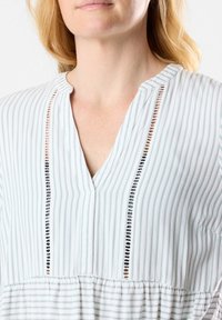Leichtes, gestreiftes Blusenshirt aus weichem Stoff; mit V-Ausschnitt, gesticktem Vorderteil und gerafftem Taillenbund. Farbpalette: hellgrün und weiß.