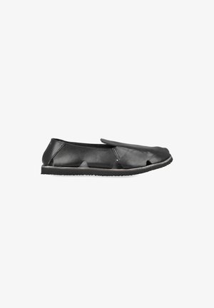 Black leather slip-on shoe with cut-out details on the sides and front, flat sole, and a rounded closed toe.