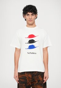 Weißes Baumwoll-T-Shirt mit drei stilisierten Hüten in Rot, Schwarz und Blau, darunter der Text „NoProblemo“ in Schwarz.