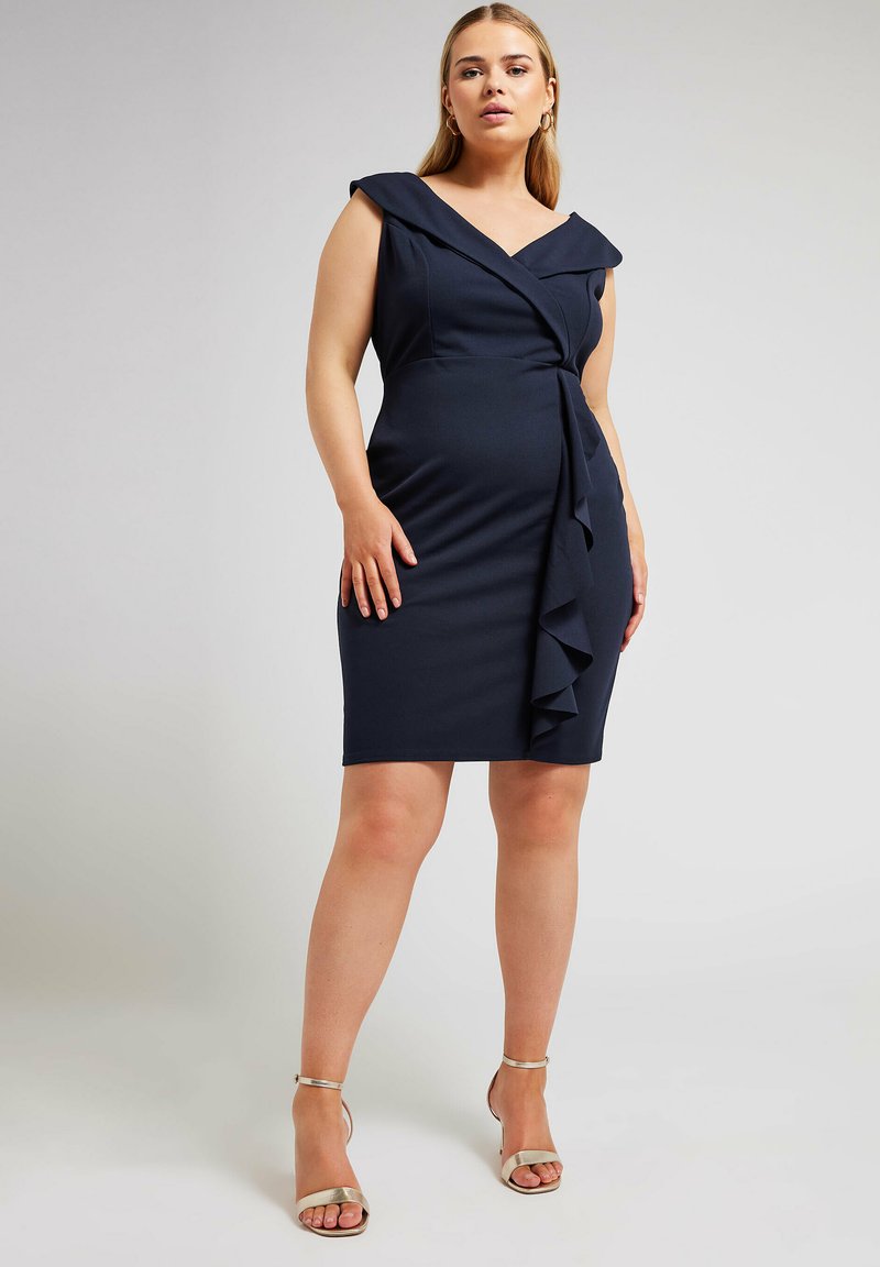 Laivastonsininen kietaisumekko, jossa on V-pääntie, lyhyet hihat ja röyhelö etuosassa. Valmistettu sileästä kankaasta, joka istuu tiiviisti.