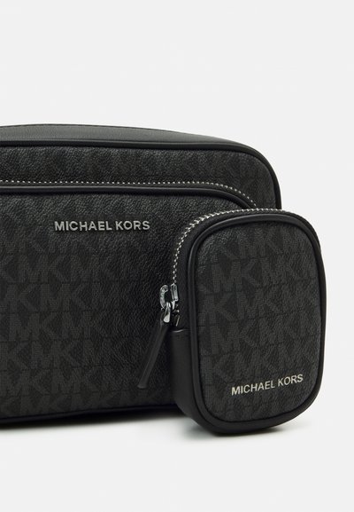 Sac bandoulière en tissu synthétique noir avec une finition texturée, des accessoires en métal argenté et une petite pochette détachable avec un détail de logo.