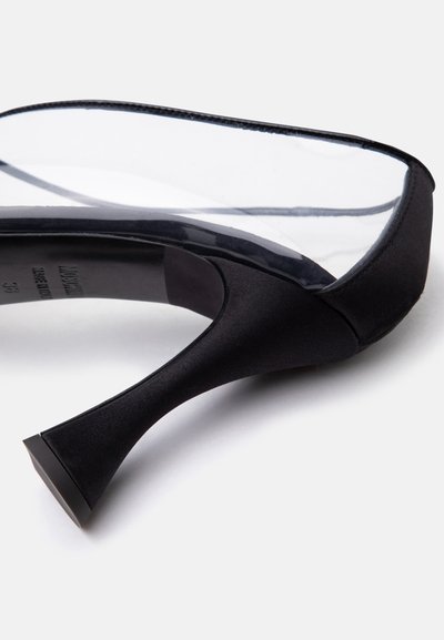 Pantof negru cu toc înalt, cu material superior transparent și bază evazată pe toc, expus pe un fundal alb.