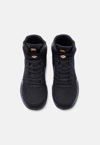 Ζευγάρι μαύρα αθλητικά παπούτσια με ψηλό κράτημα, κατασκευασμένα από διχτυωτό ύφασμα, με κορδόνια και χρυσό λογότυπο φιδιού στη γλώσσα, απεικονιζόμενα από πάνω σε λευκό φόντο.