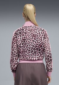 Leopard-print trui in roze stof met lange mouwen, geribbelde manchetten en kraag. Gladde textuur met donkere luipaardvlekken.