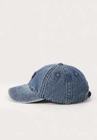 Denim baseball cap med bøjet skygge, blå stof, kontrasterende syninger og et lille logo-patch foran. Justerbar rem bagpå.