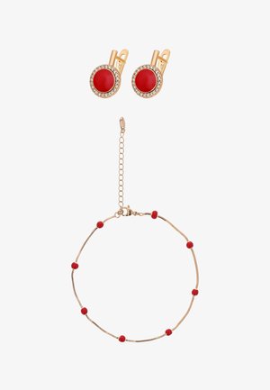 Goldenes Armband mit kleinen roten Perlen und goldene Ohrringe mit großen roten Mittelteilen, umgeben von klaren Steinen.