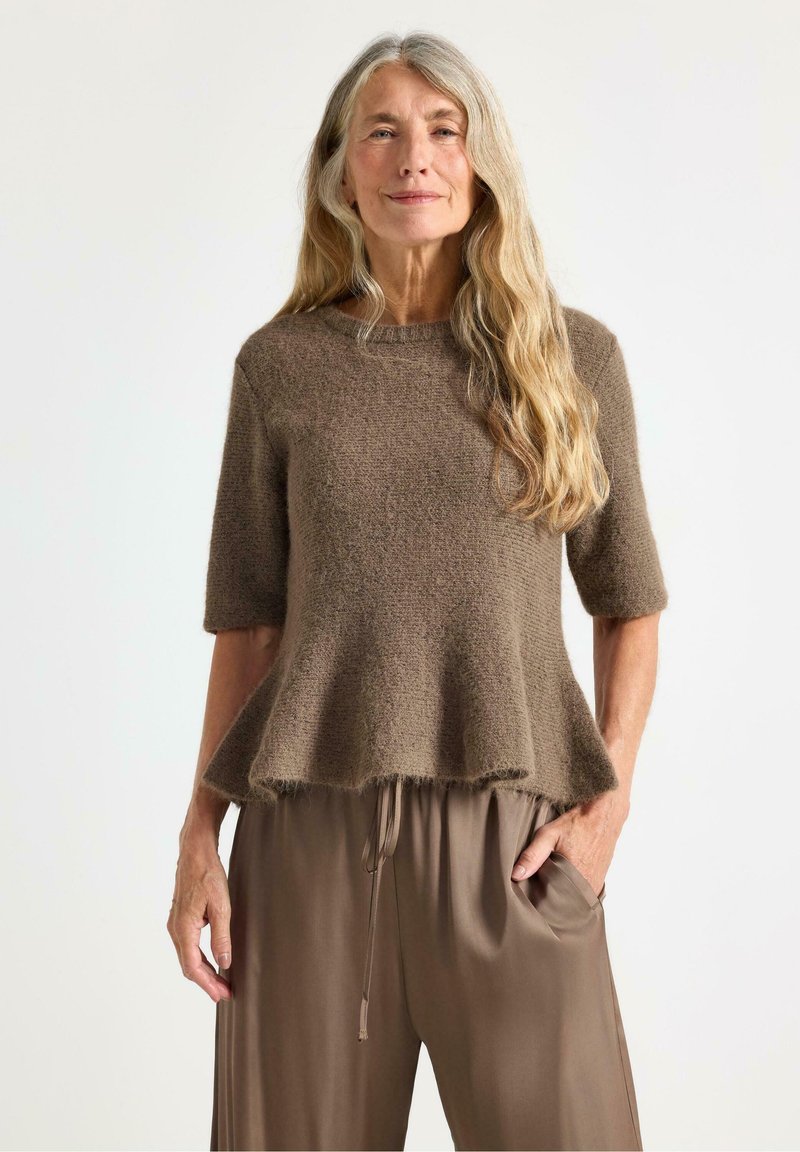 Maglione corto a maniche corte di colore marrone, in maglia testurizzata, con orlo svasato. Abbinato a pantaloni larghi marroni con coulisse. Design morbido e rilassato.