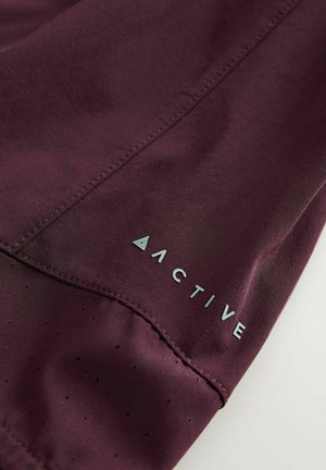 Bordo atletski materijal s glatkom teksturom; sadrži perforacije i svijetloplavi logo s natpisom "ACTIVE" blizu ruba.