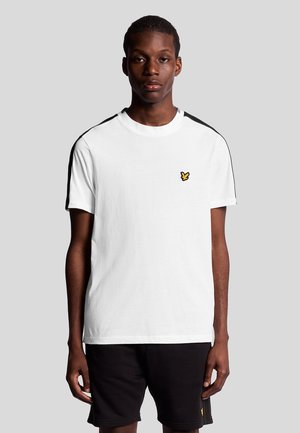 T-shirt en coton blanc avec des bandes noires sur les épaules et un petit logo jaune sur la poitrine. Manches courtes et coupe ras du cou.