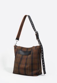 Rjava karičasta torba z črnim usnjenim detajlom, nastavljivim trakom z srebrnimi elementi in zadrgo na vrhu.