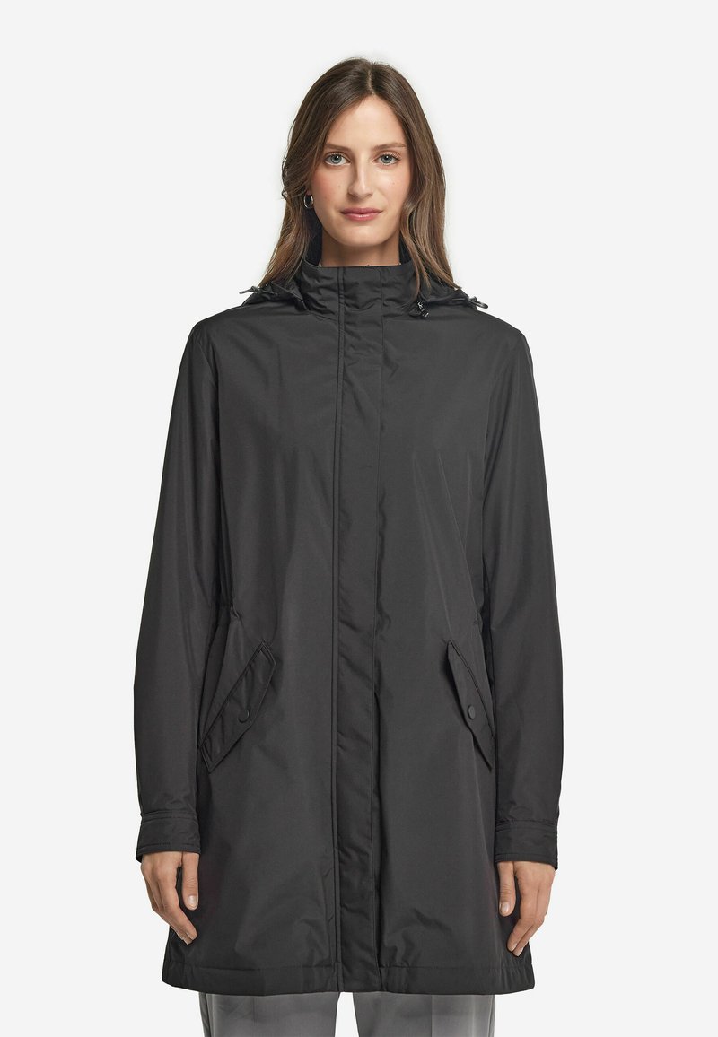 Svart vattentät jacka med hög krage, långa ärmar och fickor på sidan med tryckknappar. Slät textur och avslappnad passform, lämplig för olika väderförhållanden.