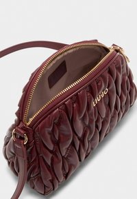 Burgunderfarbene Lederhandtasche mit gestepptem Design, goldfarbigem Reißverschluss und verstellbarem Tragegurt. Das Innere ist gefüttert und verfügt über ein Markenlabel.