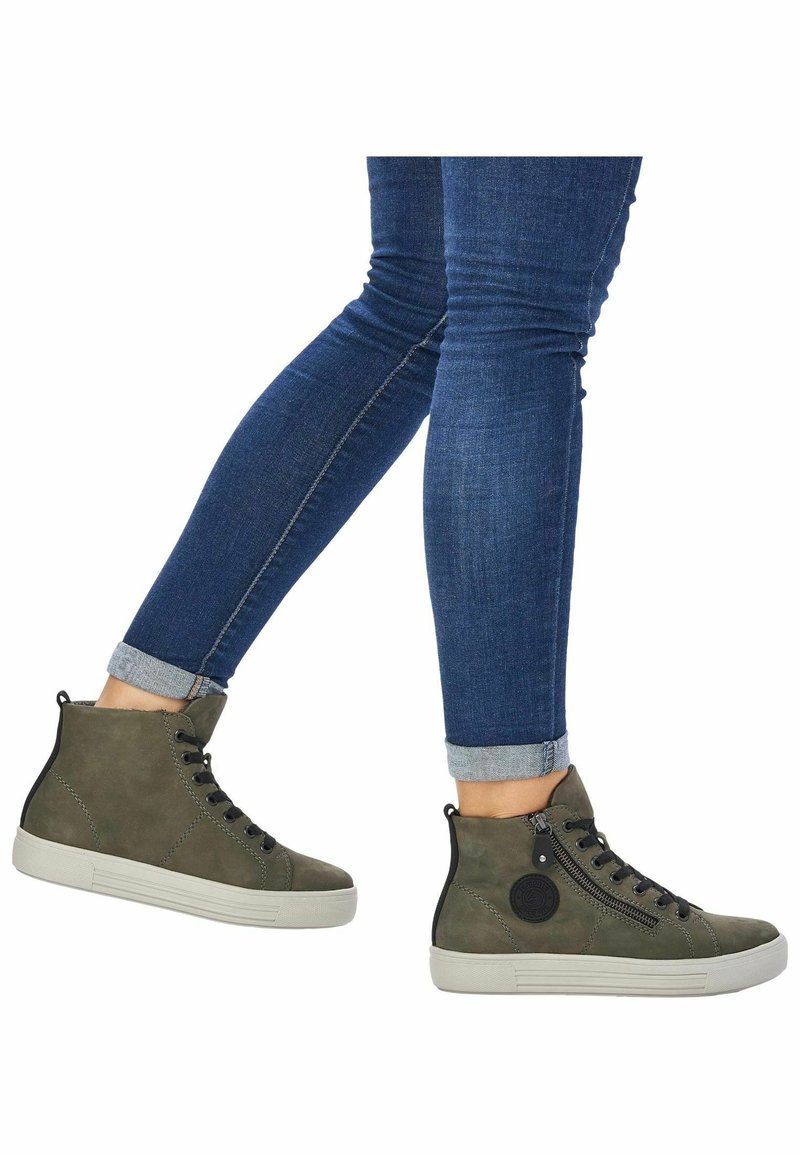 Baskets montantes vert olive en daim avec des accents noirs, dotées d'une fermeture éclair, de lacets noirs et d'une semelle en caoutchouc texturée.