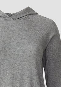 Close-up van een heidegrijze hoodie die de textuur van de stof en de naaddetails op de schouder en kap toont.