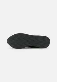 Black rubber shoe sole, featuring a textured zigzag pattern for traction, with smooth edges and no visible wear or embellishments.