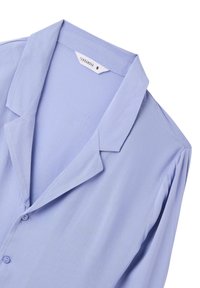 Blusa lilla chiaro realizzata in tessuto morbido. Presenta un colletto a scollo a V, bottoni frontali e sottili arricciature sulle spalle. L'etichetta indica la taglia S.