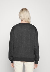 Felpa grigia scura con una vestibilità comoda, polsini e orlo a coste e una texture liscia. Presenta un classico scollo a girocollo.