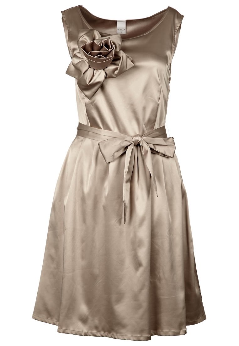 Satin beige klänning med en figursydd överdel, breda axlar och en stor blomma som accent. Har en midja med bälte och en A-linjär kjol.