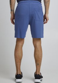 Shorts blu textured con una vestibilità rilassata e una tasca posteriore. Indossati con sneaker nere con suole bianche.