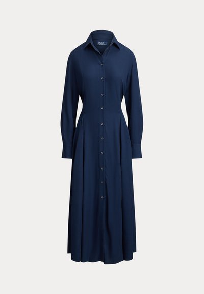 Φόρεμα σε ναυτικό μπλε χρώμα με κουμπιά, γιακά, μακριά μανίκια και πλισέ φούστα. Κατασκευασμένο από λεία ύφασμα, με κλασική σιλουέτα.