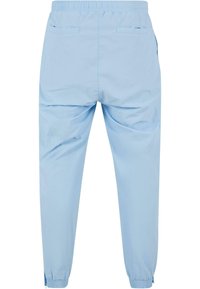 Light blue jogger pants made of smooth fabric, featuring an elastic waistband, two back pockets, and elastic cuffs at the ankles.