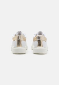 Sneaker bianchi con accenti metallici dorati sul tallone, tomaia in pelle liscia, suola in gomma piatta e logo ricamato sul retro.