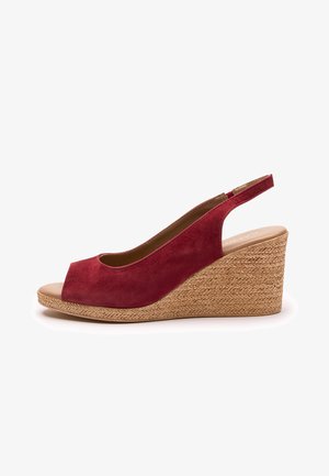 Czerwony sandał na klinie zamszowy, z odkrytym palcem i paskiem na pięcie. Posiada klinowy obcas z plecionej juty, dodający wysokości i faktury.