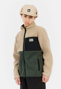 Fleece jack in bruin, groen en zwart. Voorzien van een ritssluiting, hoge kraag en contrasterende texturen. Logopatch op de borst.