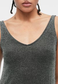 Fémes fekete ujjatlan felső V-nyakkal. Simább tapintású, finom fényű, széles pántokkal és testhez simuló fazonnal.