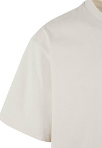 Lys beige bomull t-skjorte med rund hals, kortermet og en glatt tekstur, som fremhever et enkelt og minimalistisk design.