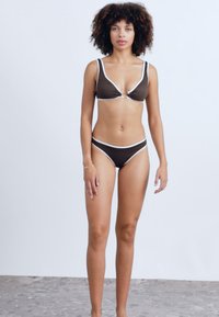 Brown bikini set featuring a triangle top with white trim and a front knot detail, paired with matching low-rise bottoms. Smooth texture.