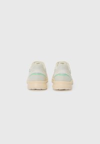 Hellgraue Sneakers mit einem Mesh-Obermaterial, grünen Akzenten und einer beigen Sohle. Sie verfügen über ein minimalistisches Design und eine abgerundete Ferse für mehr Komfort.
