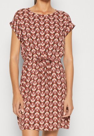 Femme portant une robe à manches courtes avec un motif floral géométrique rose et marron et une ceinture nouée à la taille.